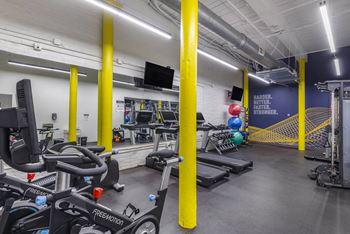 A gym with cardio equipment and weights in a building
